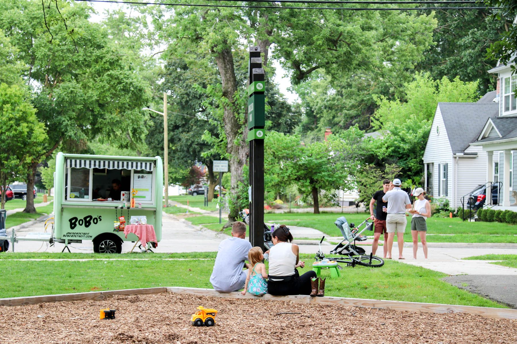 Neighbors gathered in a Royal Oak pocket park on a summer evening, with a food truck parked on the street